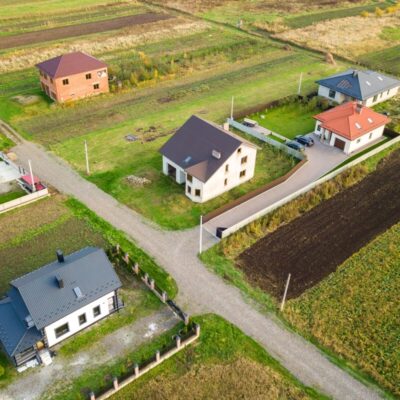Na zdjęciu widać rozłożyste tereny wiejskie zabudowane wśród zieleni, gdzie znajdują się domy parterowe stalowe.