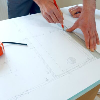 Mężczyzna rysuje projekty domów stalowych na papierze technicznym.
