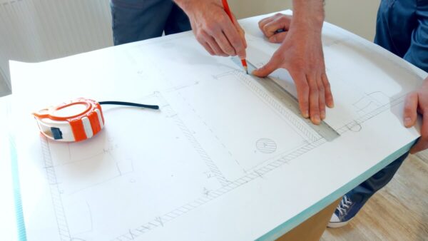 Mężczyzna rysuje projekty domów stalowych na papierze technicznym.