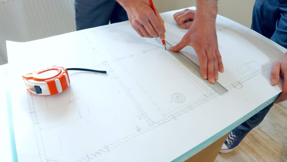 Mężczyzna rysuje projekty domów stalowych na papierze technicznym.
