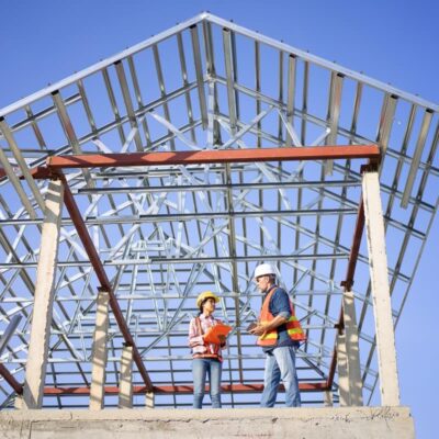 Dwóch inżynierów omawia projekty domów stalowych przy konstrukcji szkieletowej.