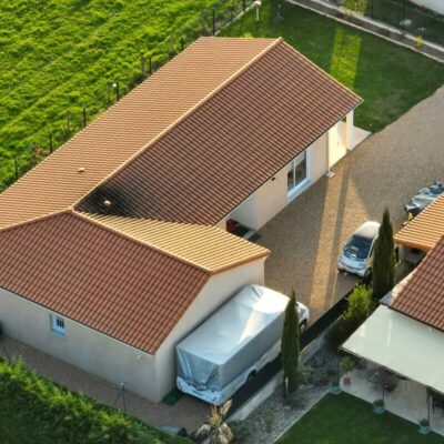 Widok z lotu ptaka na osiedle, gdzie domy stalowe posiadają czerwone dachówki.
