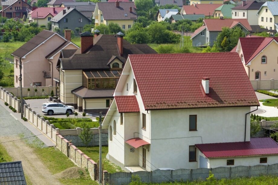 Osiedle z nowoczesnymi domami z poddaszem i czerwonymi dachami.