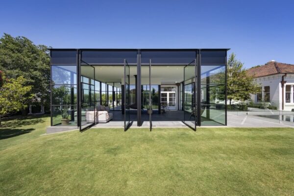 Przestronny nowoczesny budynek ze szkła obok tradycyjne domy stalowe.