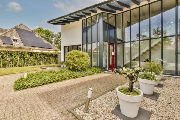 Nowoczesny budynek z dużymi oknami, przypominający tradycyjne domy stalowe.